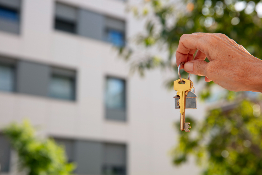 Hand holding keys in front of a living property